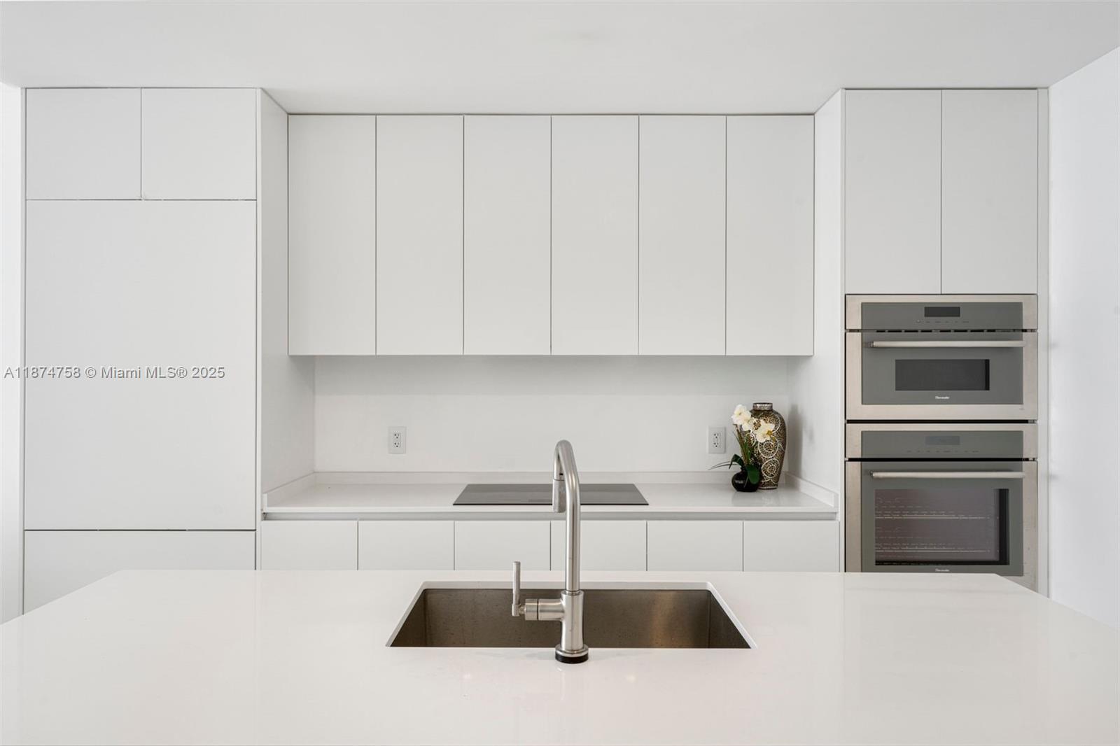 700 Northeast 24th Street, Unit 1005 Miami, FL 33137 - Photo 5 of 18 a kitchen with a sink and white cabinets