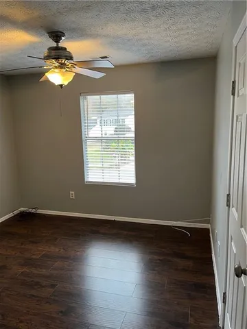 an empty room with wooden floor chandelier fan and windows