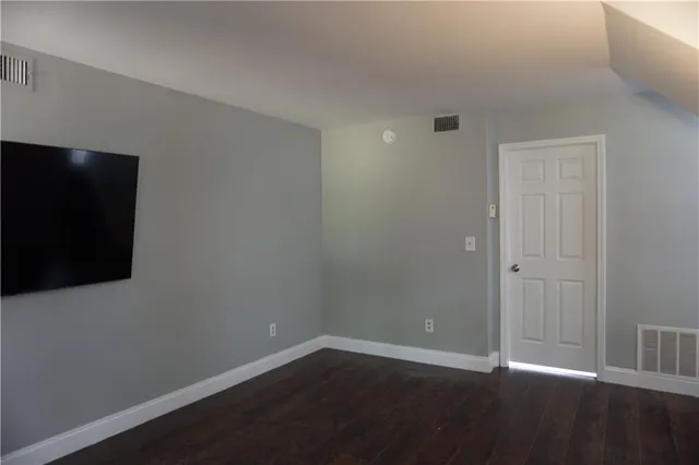 a view of an empty room with wooden floor and closet