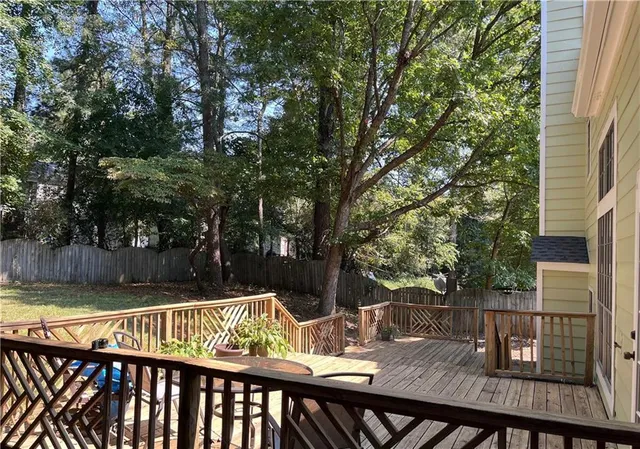 a view of backyard with two large trees and wooden fence