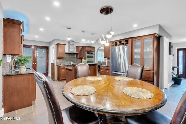 a kitchen with stainless steel appliances kitchen island granite countertop a table chairs sink and cabinets