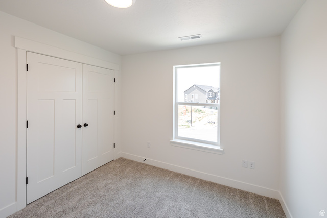 195 West Harmony Rdg Parkway, Unit 601 Mapleton, UT 84664 - Photo 14 of 23 Interior space featuring neutral wall paint, gray carpeting, a single window with white trim, white baseboards, and a double-door closet with black hardware