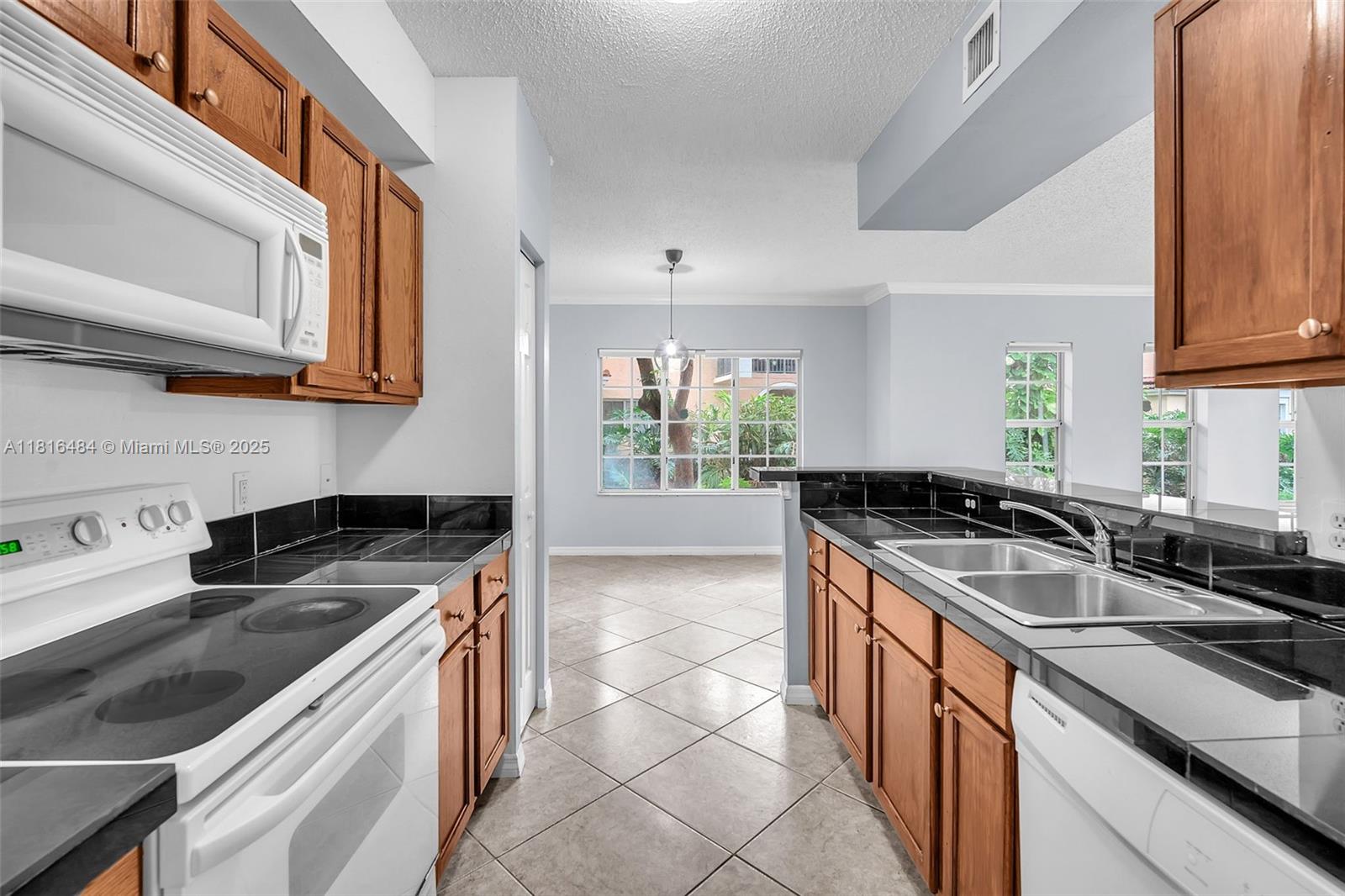 2474 Centergate Drive, Unit 101 Miramar, FL 33025 - Photo 6 of 28 a kitchen with a sink stove top oven and cabinets