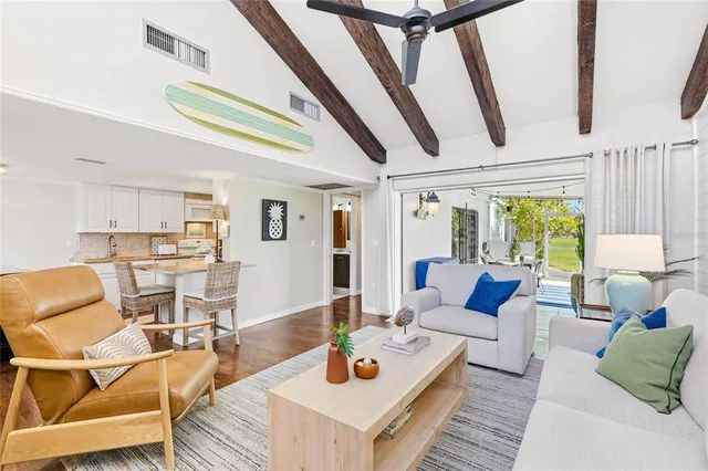 a living room with stainless steel appliances granite countertop furniture and a wooden floor