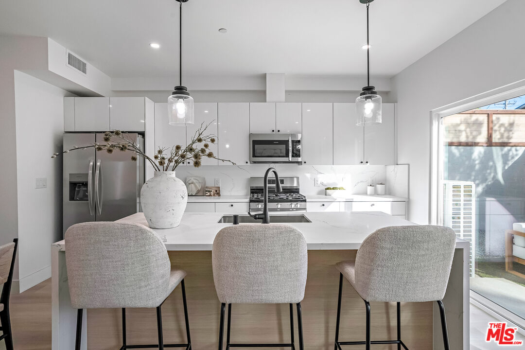 5830 David Avenue Los Angeles, CA 90034 - Photo 10 of 46 a kitchen with stainless steel appliances granite countertop a table chairs refrigerator and microwave