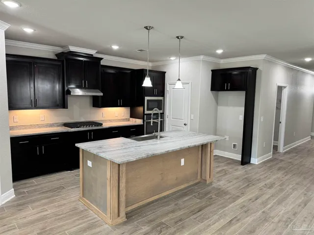 a large kitchen with stainless steel appliances kitchen island granite countertop a large counter top and wooden floors