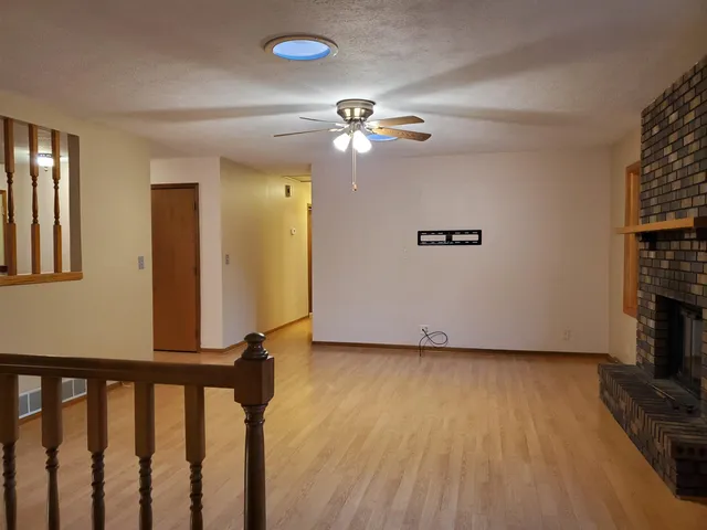 a view of an empty room with window and wooden floor