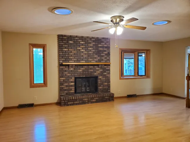 a view of an empty room with a fireplace and wooden floor