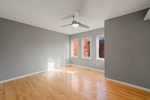 a view of empty room with wooden floor and ceiling fan
