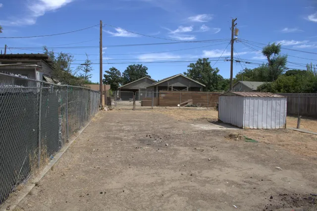 a view of a house with a dry yard and a wooden fence