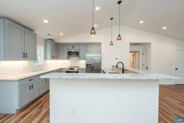 a kitchen with stainless steel appliances granite countertop a sink a stove and a refrigerator