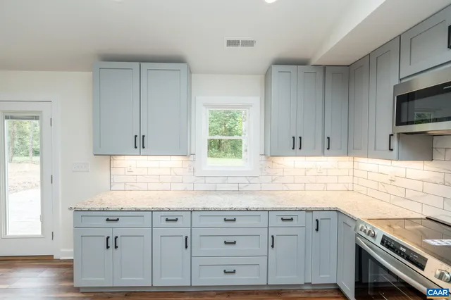 a kitchen with granite countertop cabinets stainless steel appliances a sink and a window
