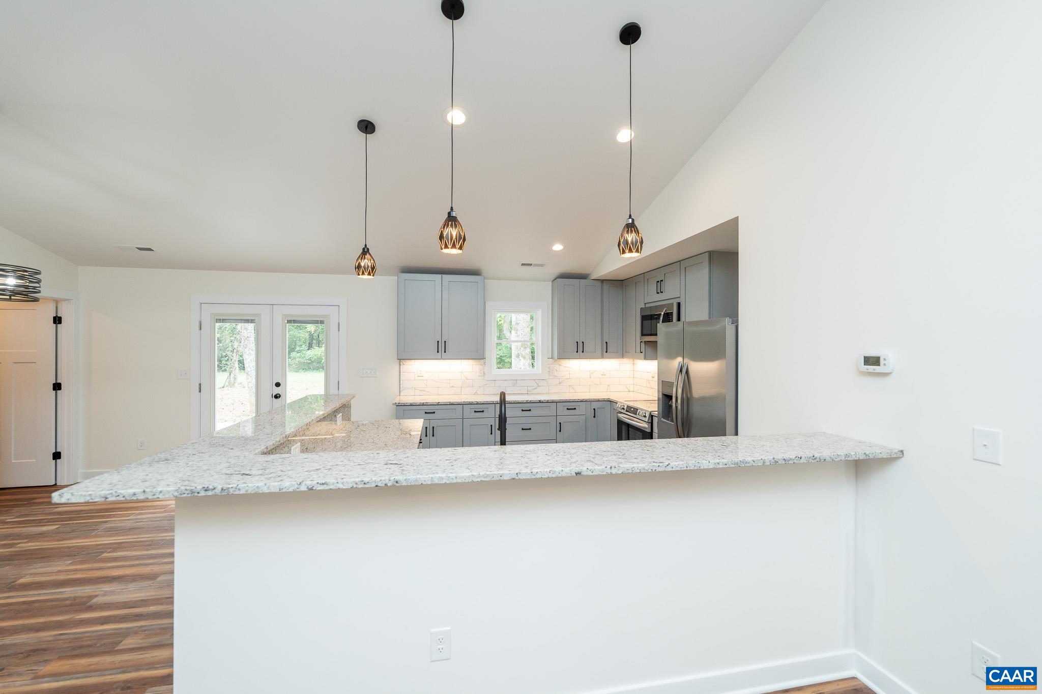 Lot 1 Ivy Road Howardsville, VA 24562 - Photo 7 of 34 a large white kitchen with a large island oven a sink dishwasher and a fireplace with wooden floor