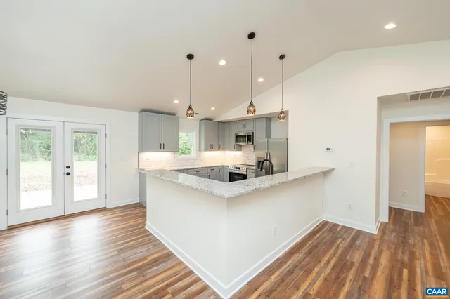 a kitchen with stainless steel appliances granite countertop a sink a stove and a wooden floor