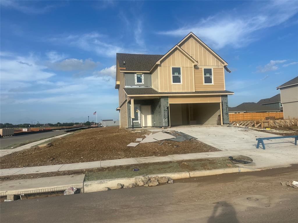 Two-story residence featuring a two-car garage, multiple windows, and a partially finished exterior with siding and sheathing