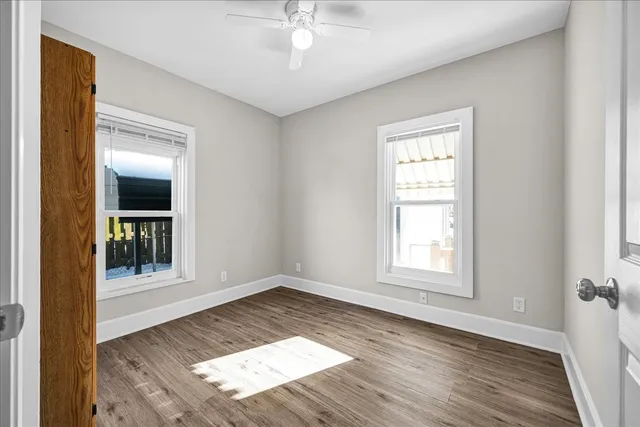 an empty room with wooden floor cabinet and windows