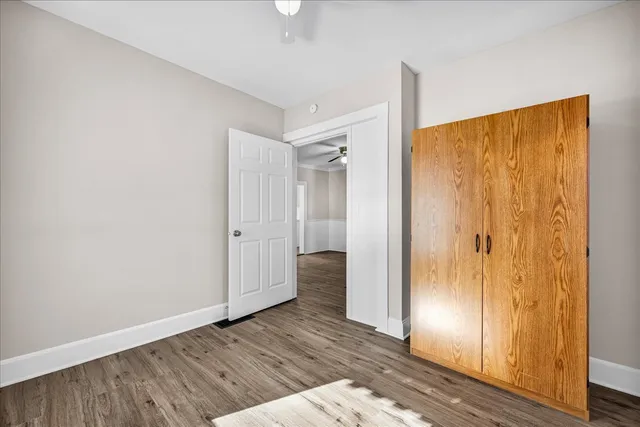 a view of an empty room with wooden floor and a bathroom