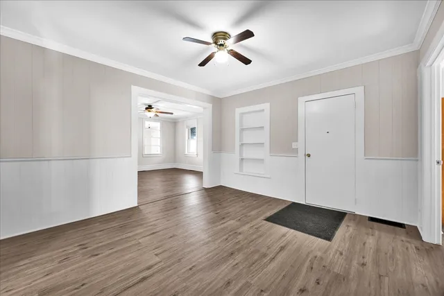 an empty room with wooden floor and windows