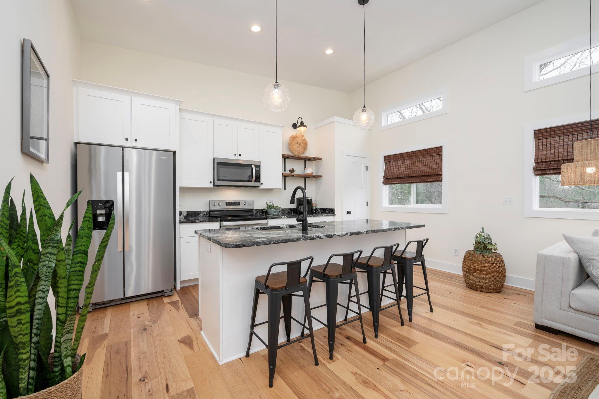 20 Garden Road Asheville, NC 28804 - Photo 12 of 44 a kitchen with stainless steel appliances granite countertop a stove a refrigerator a kitchen island a dining table and chairs with wooden floor