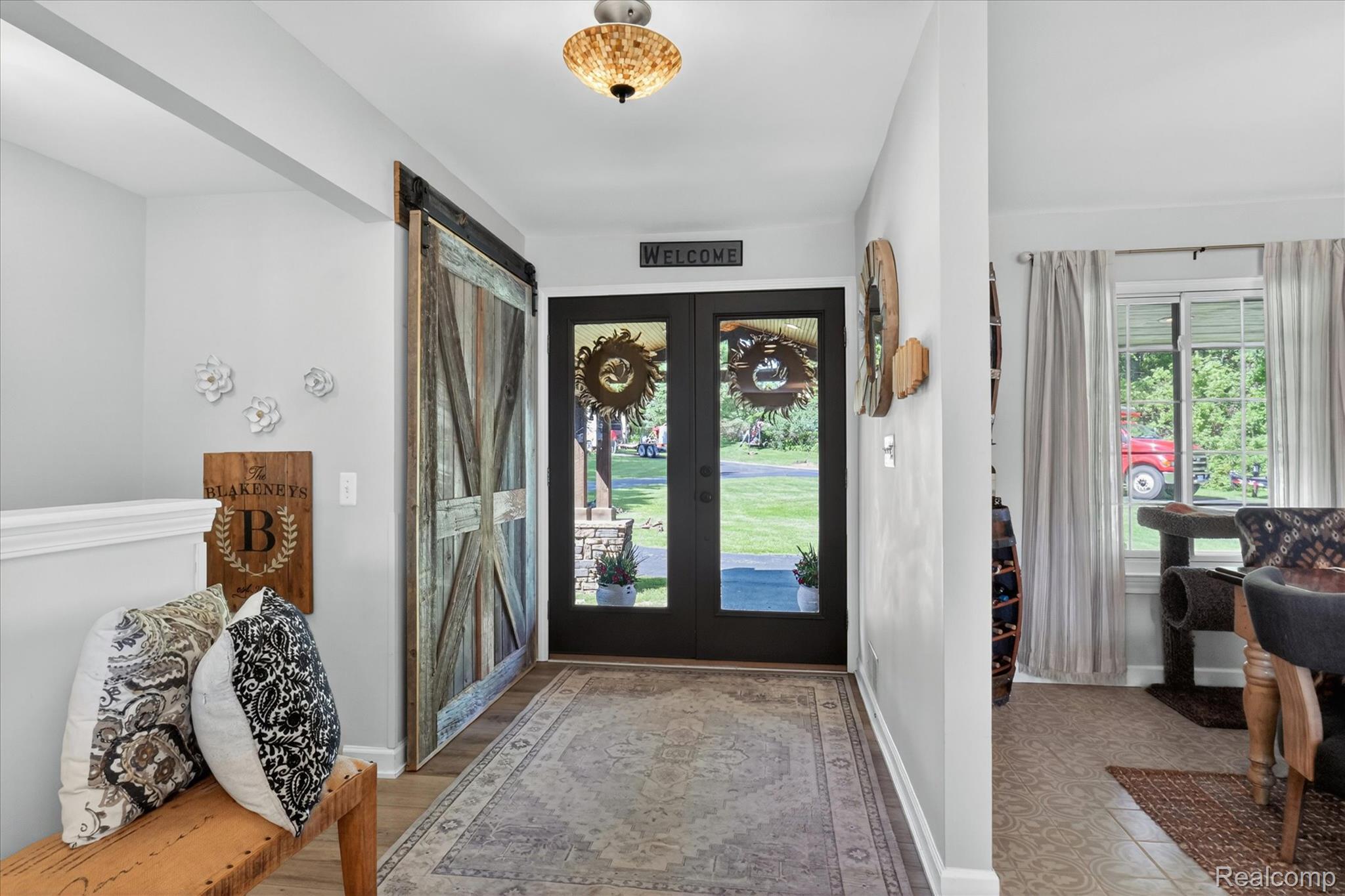 3860 East Commerce Road Commerce Township, MI 48382 - Photo 6 of 72 Entryway featuring a wood-finish barn door, double glass-paneled entry doors, and a decorative ceiling light fixture
