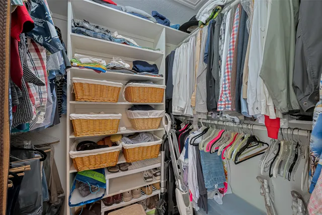 a view of walk in closet with clothes and shoes