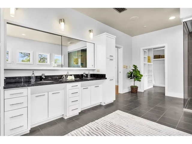a spacious bathroom with a granite countertop sink and a mirror