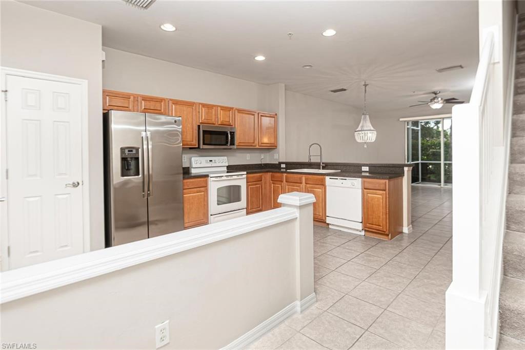 16250 Ravina Way, Unit 87 Naples, FL 34110 - Photo 5 of 15 a kitchen with stainless steel appliances granite countertop a refrigerator a stove top oven and sink