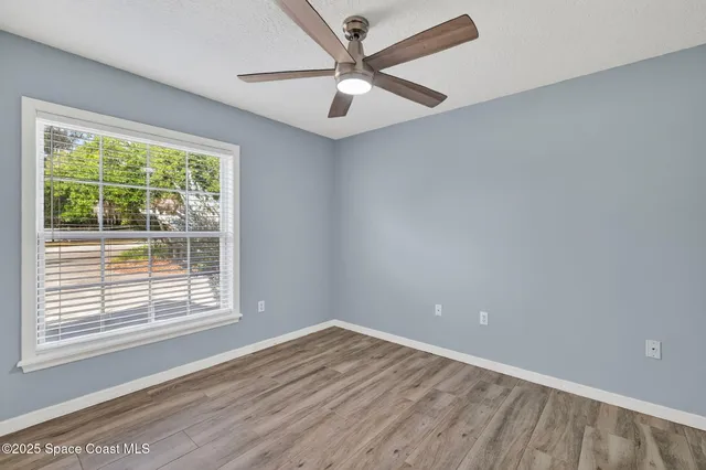 an empty room with a window and a fan