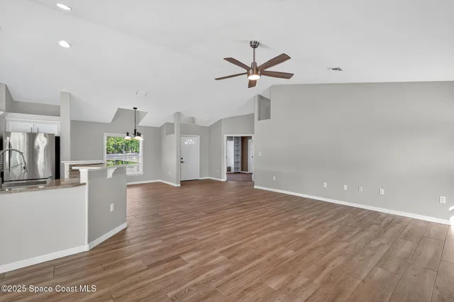 a view of a room with wooden floor and ceiling fan