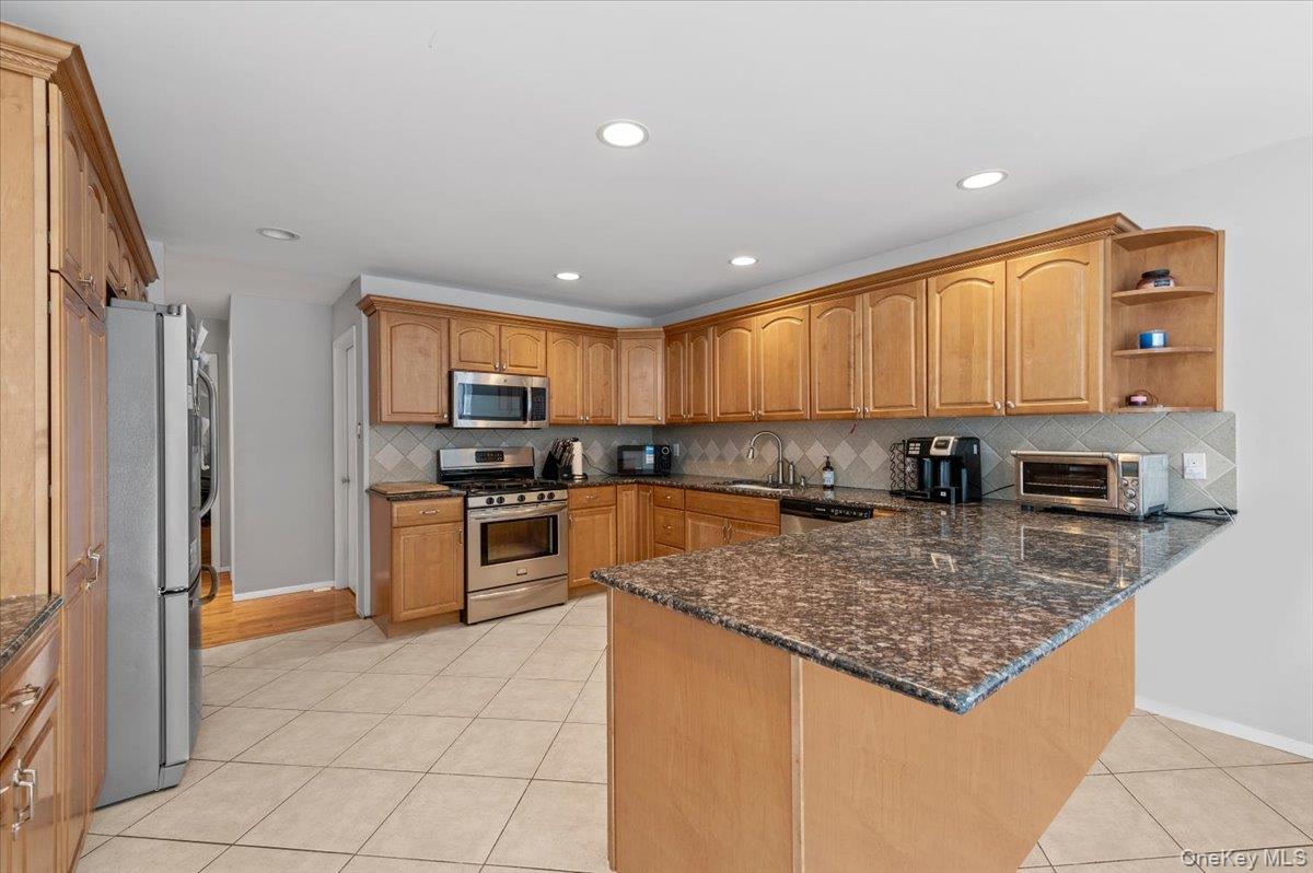 24 Wisteria Drive Remsenburg, NY 11960 - Photo 4 of 44 a kitchen with stainless steel appliances granite countertop a stove top oven a sink a refrigerator and a granite counter tops