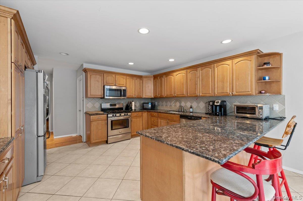 24 Wisteria Drive Remsenburg, NY 11960 - Photo 5 of 44 a kitchen with stainless steel appliances granite countertop a stove top oven a sink and a refrigerator