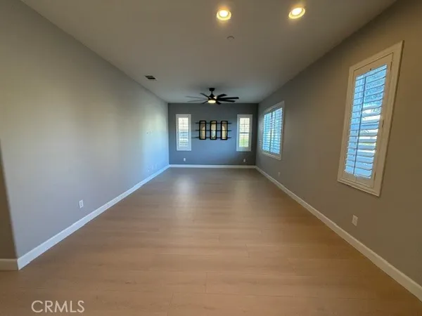 an empty room with a windows and chandelier fan