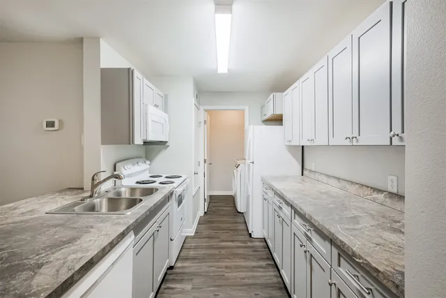 a kitchen with granite countertop a sink a stove and refrigerator