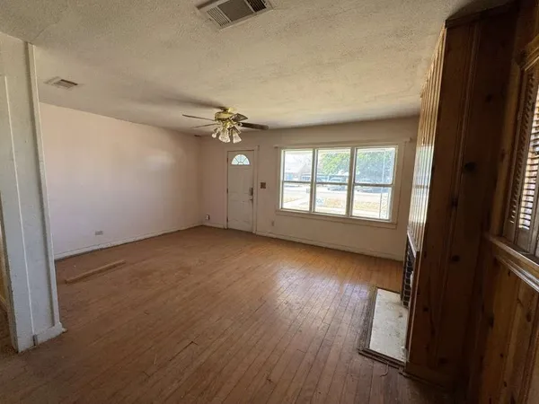 an empty room with wooden floor and windows