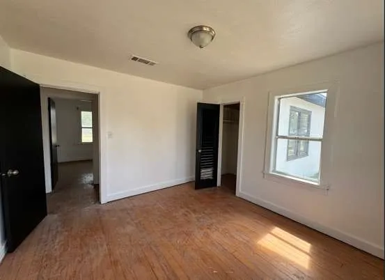 an empty room with wooden floor and windows
