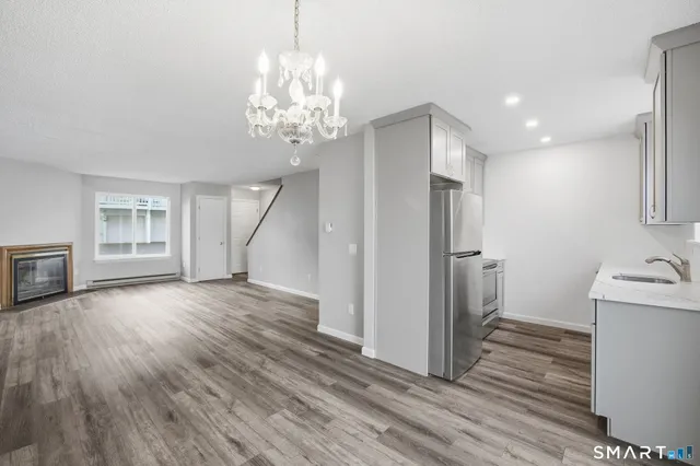 a view of a livingroom with wooden floor and a kitchen