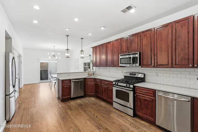 a kitchen with stainless steel appliances granite countertop wooden cabinets a stove top oven a sink and dishwasher