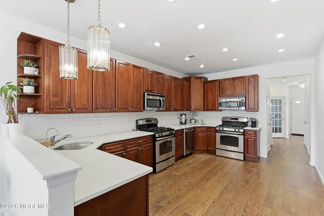 a kitchen with stainless steel appliances granite countertop wooden cabinets a stove top oven a sink and dishwasher