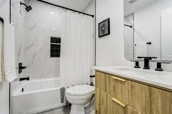 a bathroom with a granite countertop sink a toilet and shower