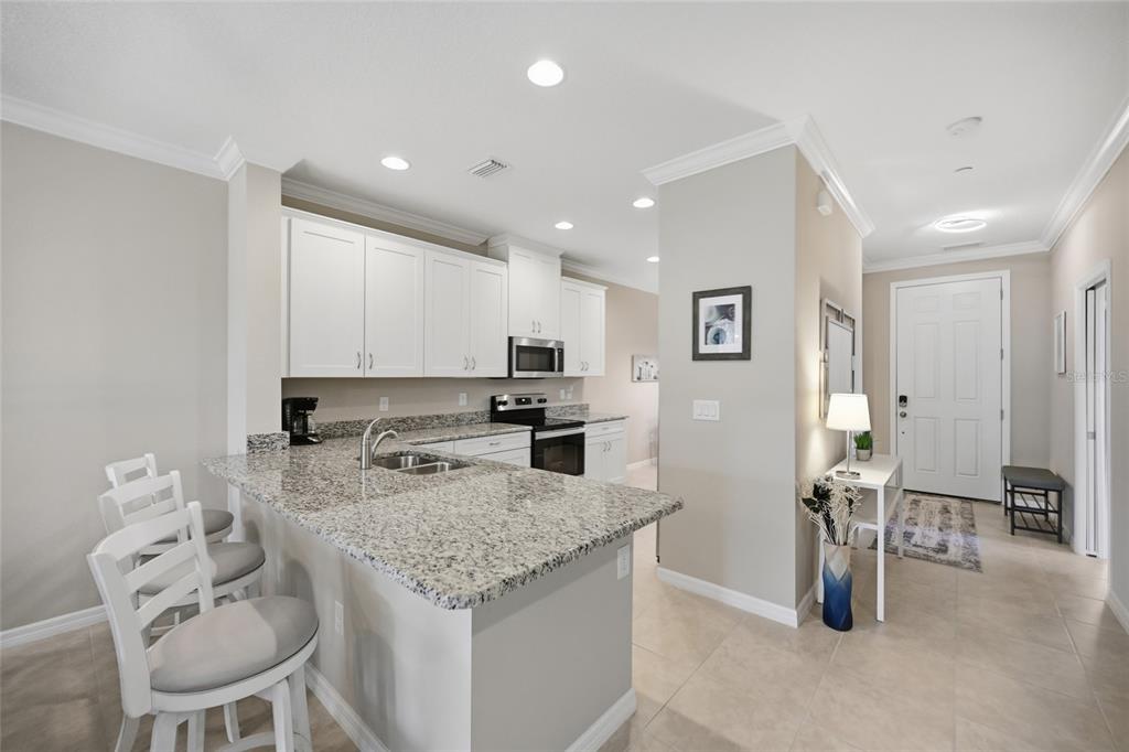 13837 Messina Loop, Unit 101 Bradenton, FL 34211 - Photo 7 of 51 a kitchen with a sink refrigerator and chairs