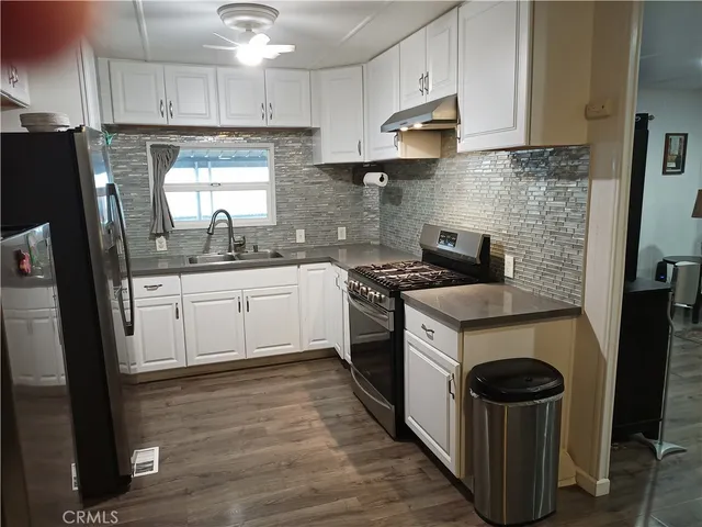 a kitchen with stainless steel appliances granite countertop a stove a sink dishwasher a refrigerator and a oven with wooden floor