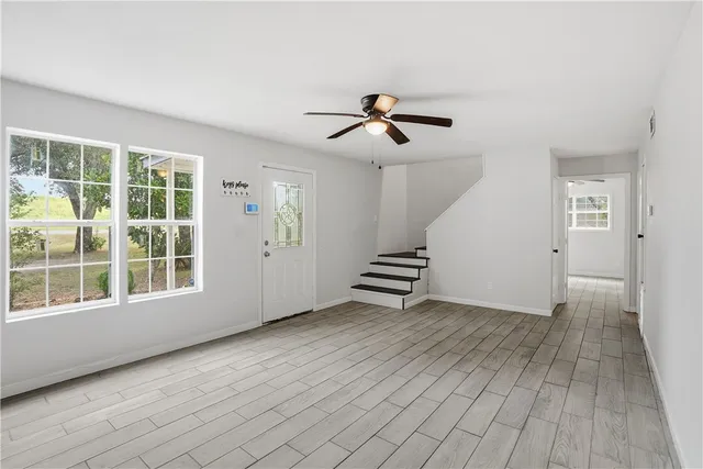 a view of an empty room with a window and wooden floor