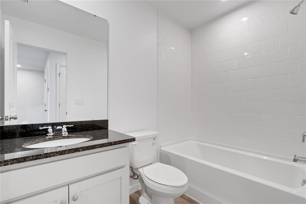 1141 Seaside Mist Trail Kissimmee, FL 34747 - Photo 17 of 30 a bathroom with a granite countertop toilet a sink and a bathtub