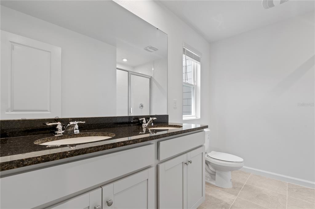 1141 Seaside Mist Trail Kissimmee, FL 34747 - Photo 26 of 30 a bathroom with a granite countertop sink a toilet and a mirror
