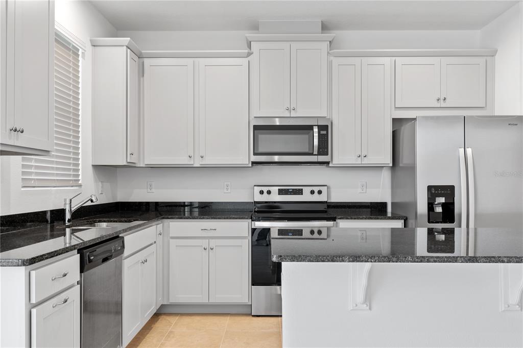 1141 Seaside Mist Trail Kissimmee, FL 34747 - Photo 6 of 30 a kitchen with granite countertop white cabinets and stainless steel appliances