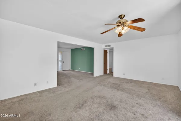 an empty room with windows and chandelier fan