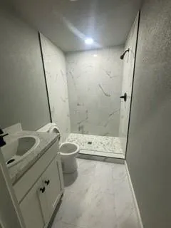 a bathroom with a granite countertop sink toilet and shower