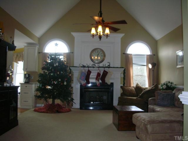 7617 Kennebec Road Willow Spring, NC 27592 - Photo 3 of 12 Cathedral ceiling, designer windows, custom mantle, gas burning logs, NEW carpet, chair rail, upgraded ceiling fan make this family room a relaxing place for the whole family to gather.
