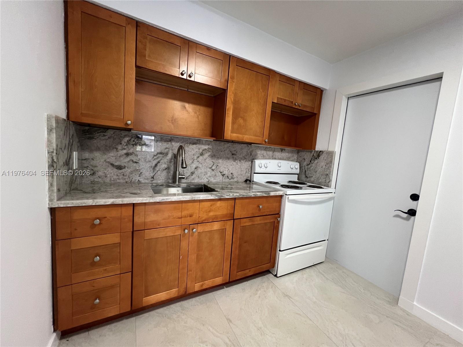 963 Northwest 5th Street, Unit 3 Miami, FL 33128 - Photo 4 of 12 a kitchen with sink a microwave and cabinets