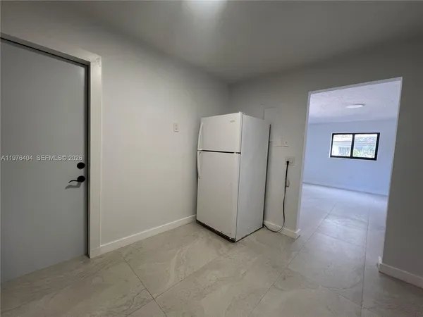an empty room with windows and refrigerator